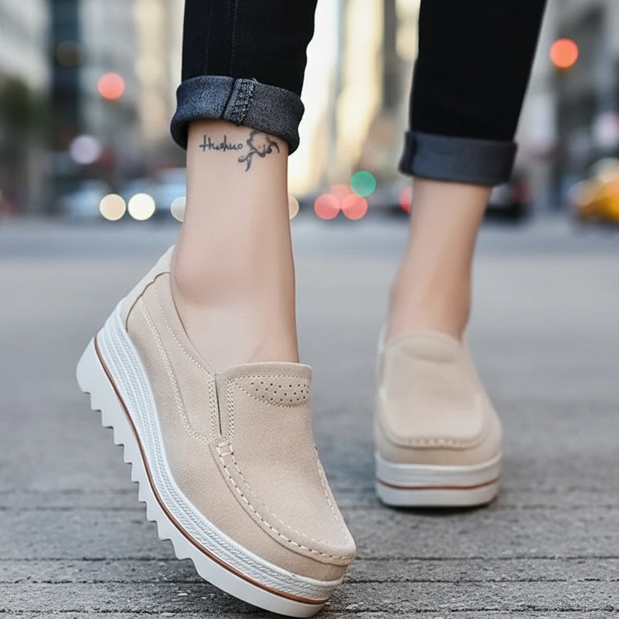 Beige slip-on shoes worn on a wooden floor